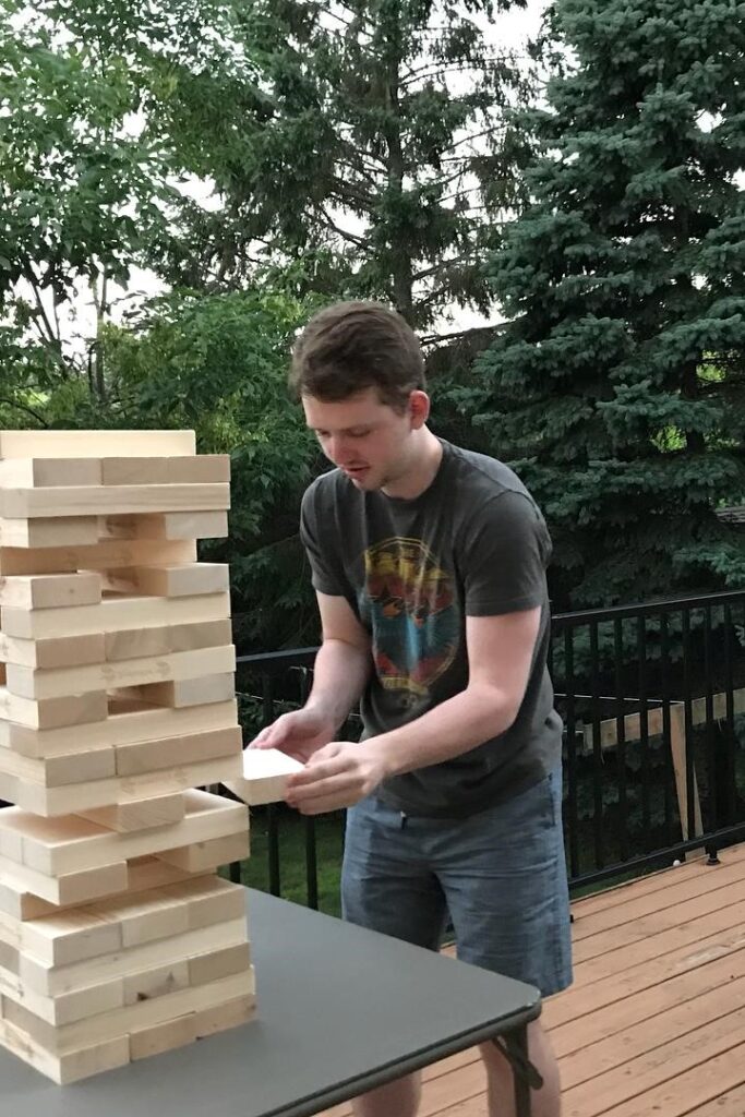 Young man playing jenga game on deck