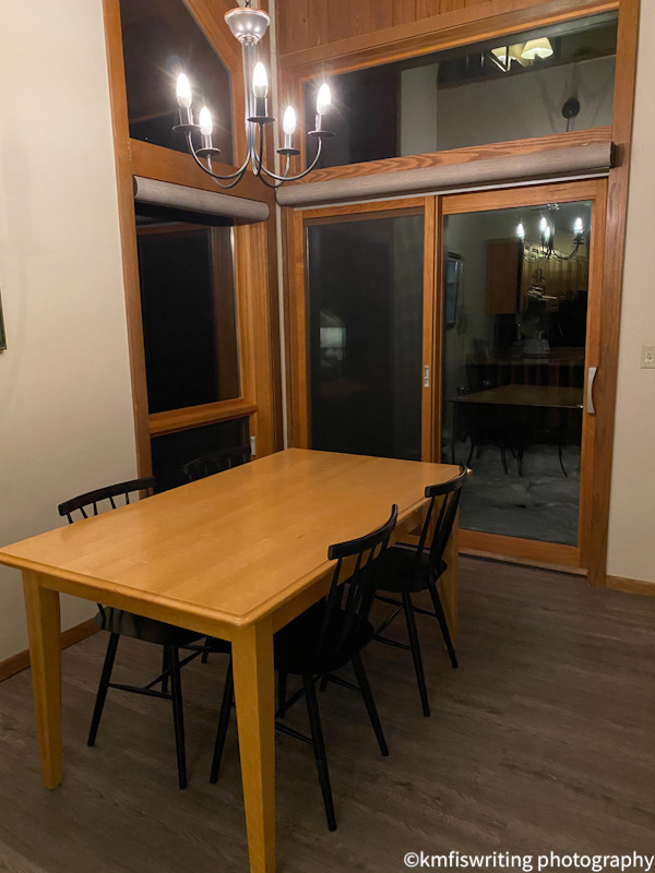 Dining room table with four chairs and a chandelier with a patio door